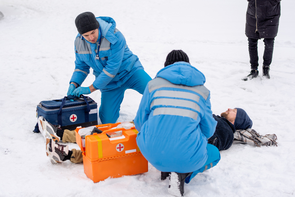 Two health and safety professionals providing first aid to a man on the snow. This is a featured image for the blog Winter Emergencies with Essential Cold Weather First Aid Techniques by Health and Safety Professionals Inc (HSPI), Ontario, Canada